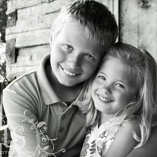 Black and white close-up portrait of siblings sharing a playful moment.
