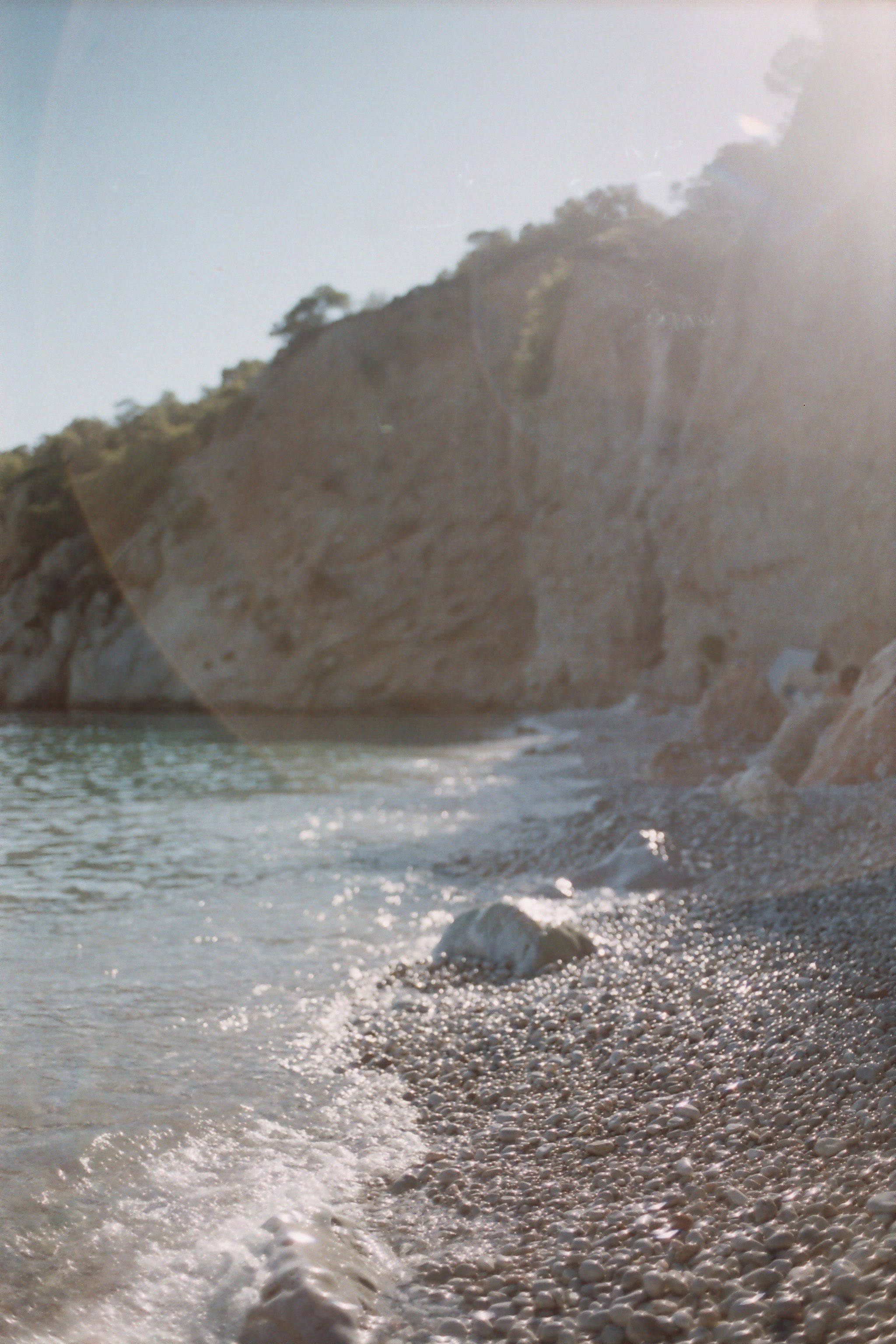 Stunning travel film capturing the beauty of Greece, showcasing a pebble beach bathed in golden sunlight