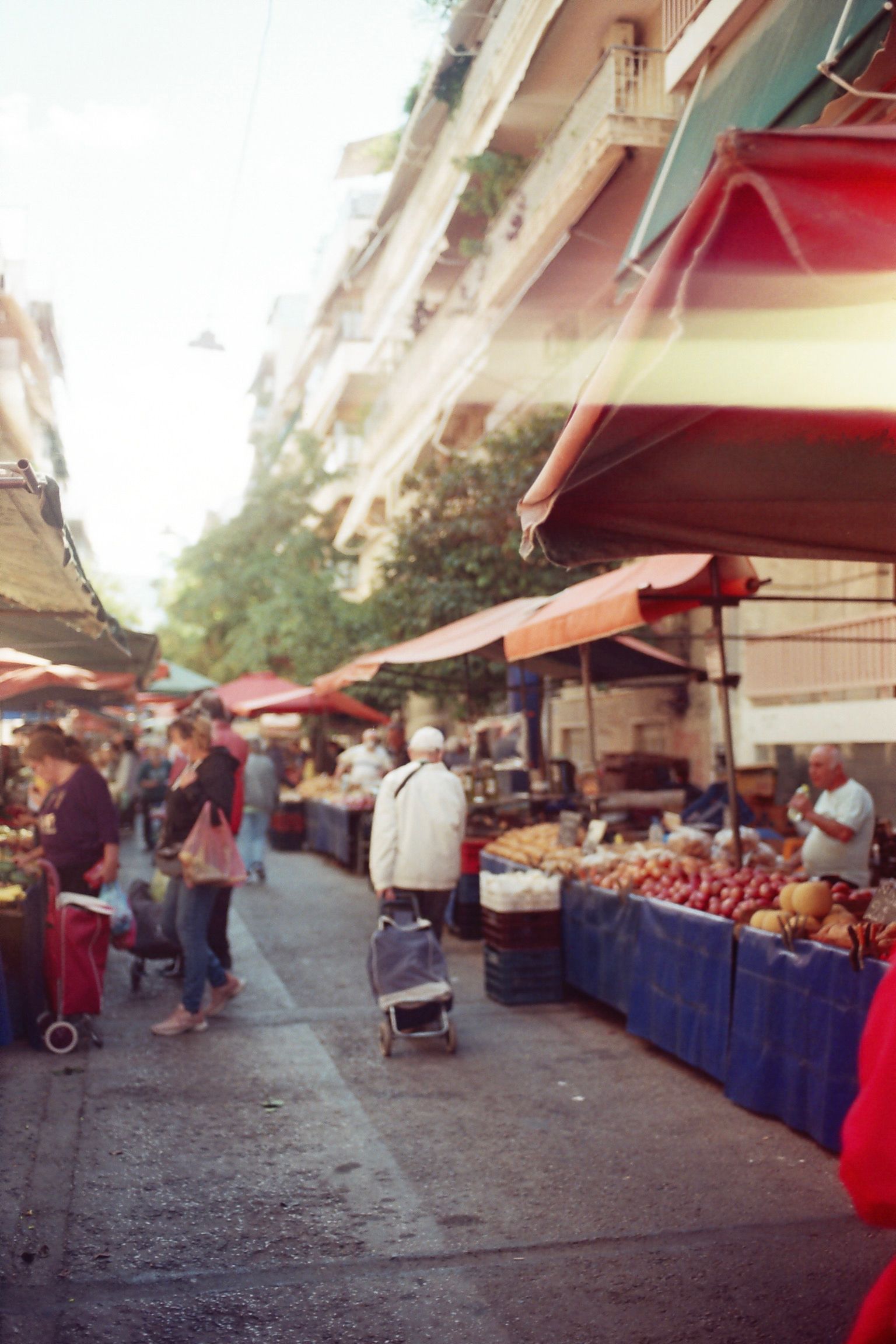Artful scenic moment captured on color film at a lively daytime market in Greece, showcasing vibrant stalls and local culture