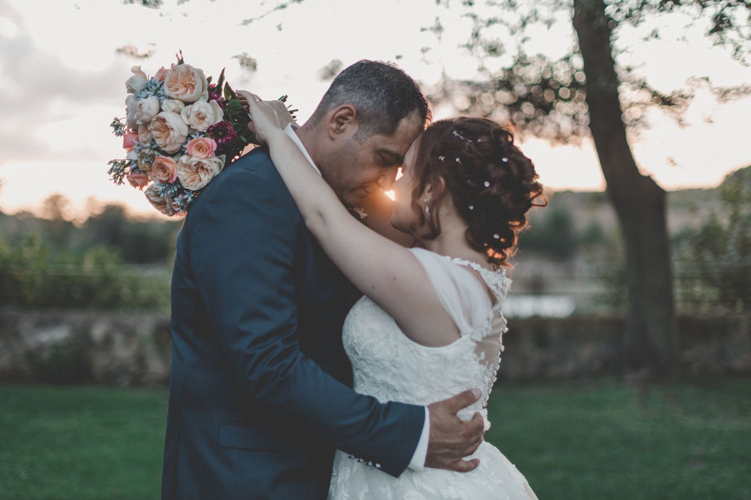 Wedding couple embracing in a romantic outdoor garden setting at sunset.