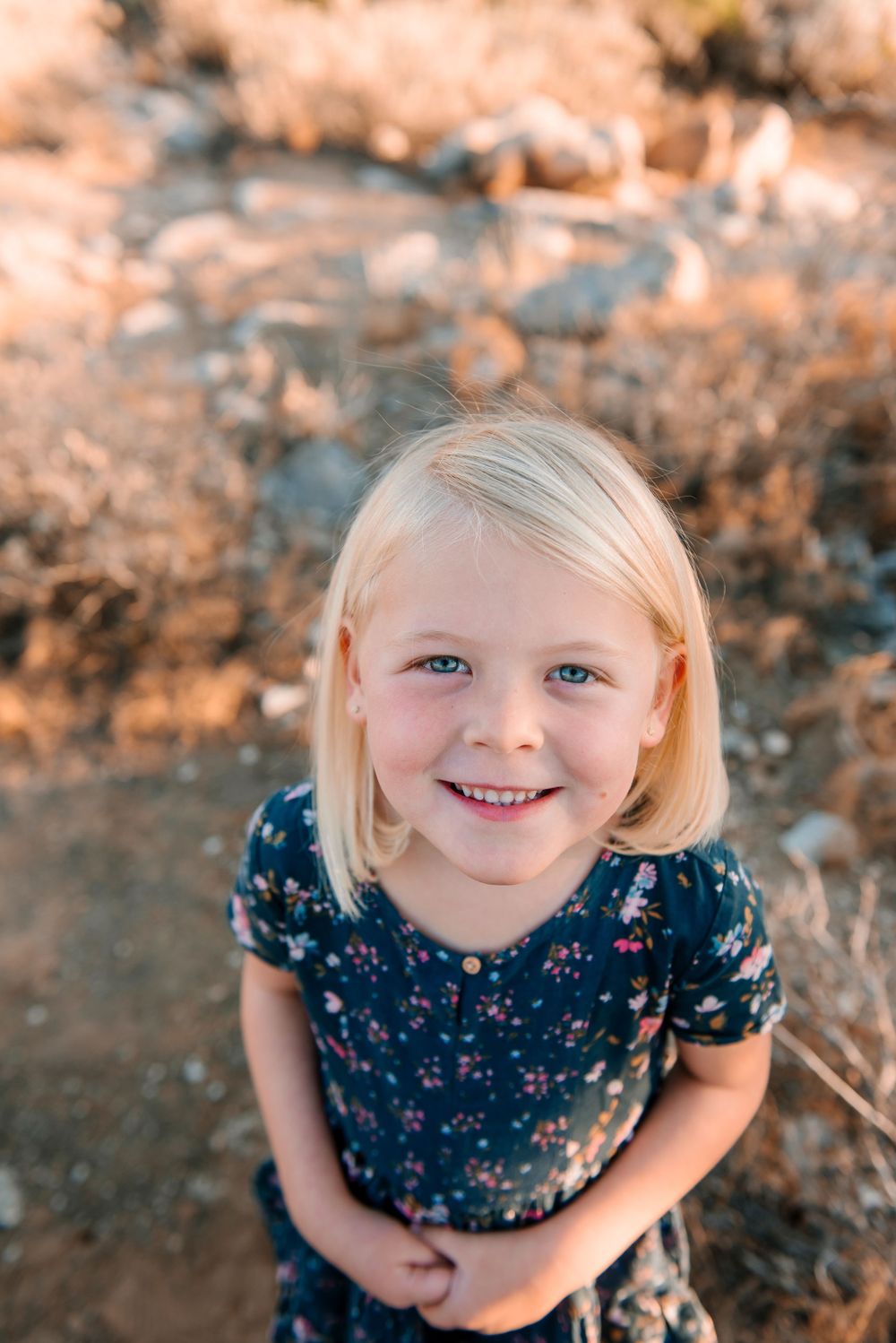 Portrait shot with desert landscape and warm lighting in background.
