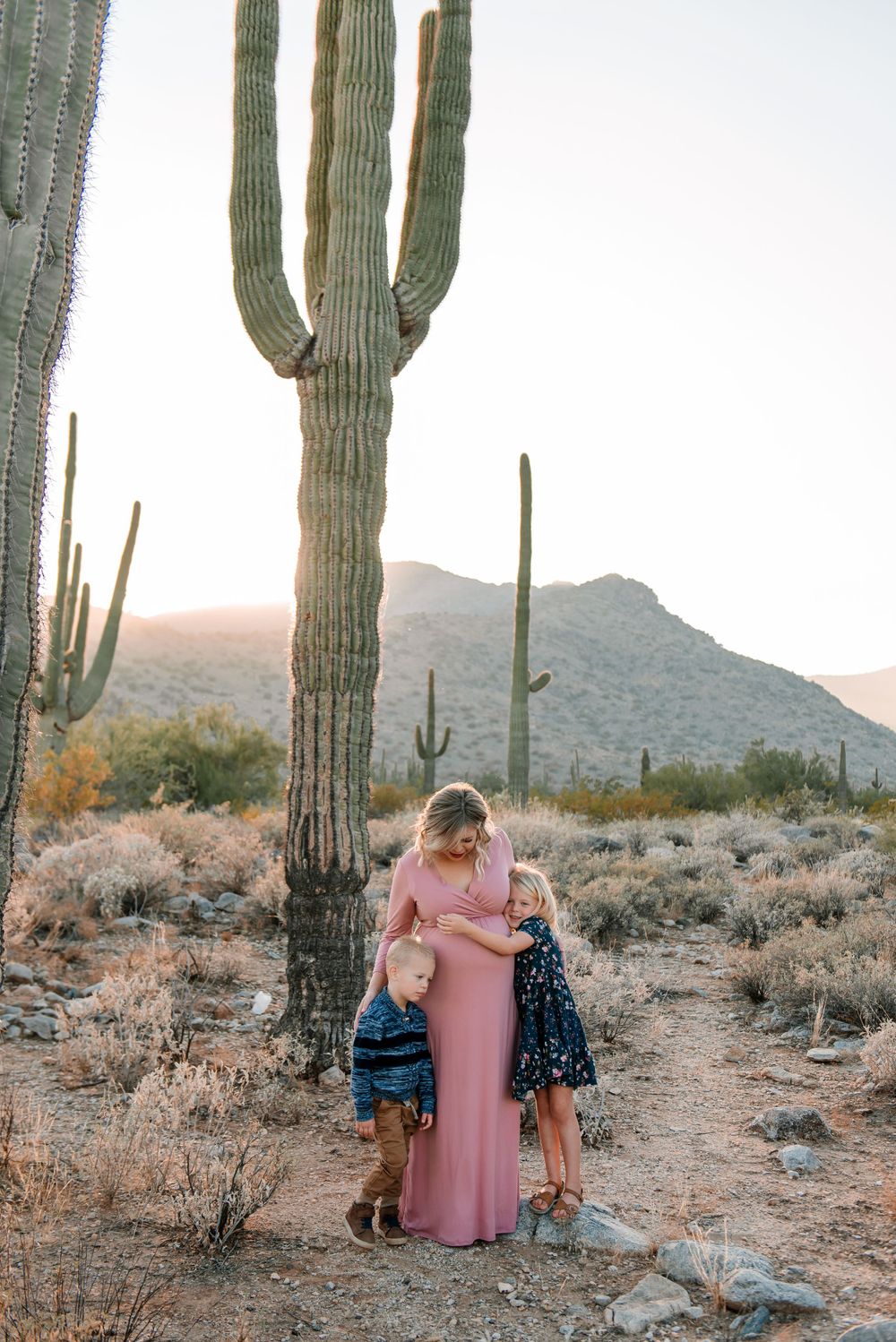 Romantic desert portrait session among towering saguaro cacti at sunset.