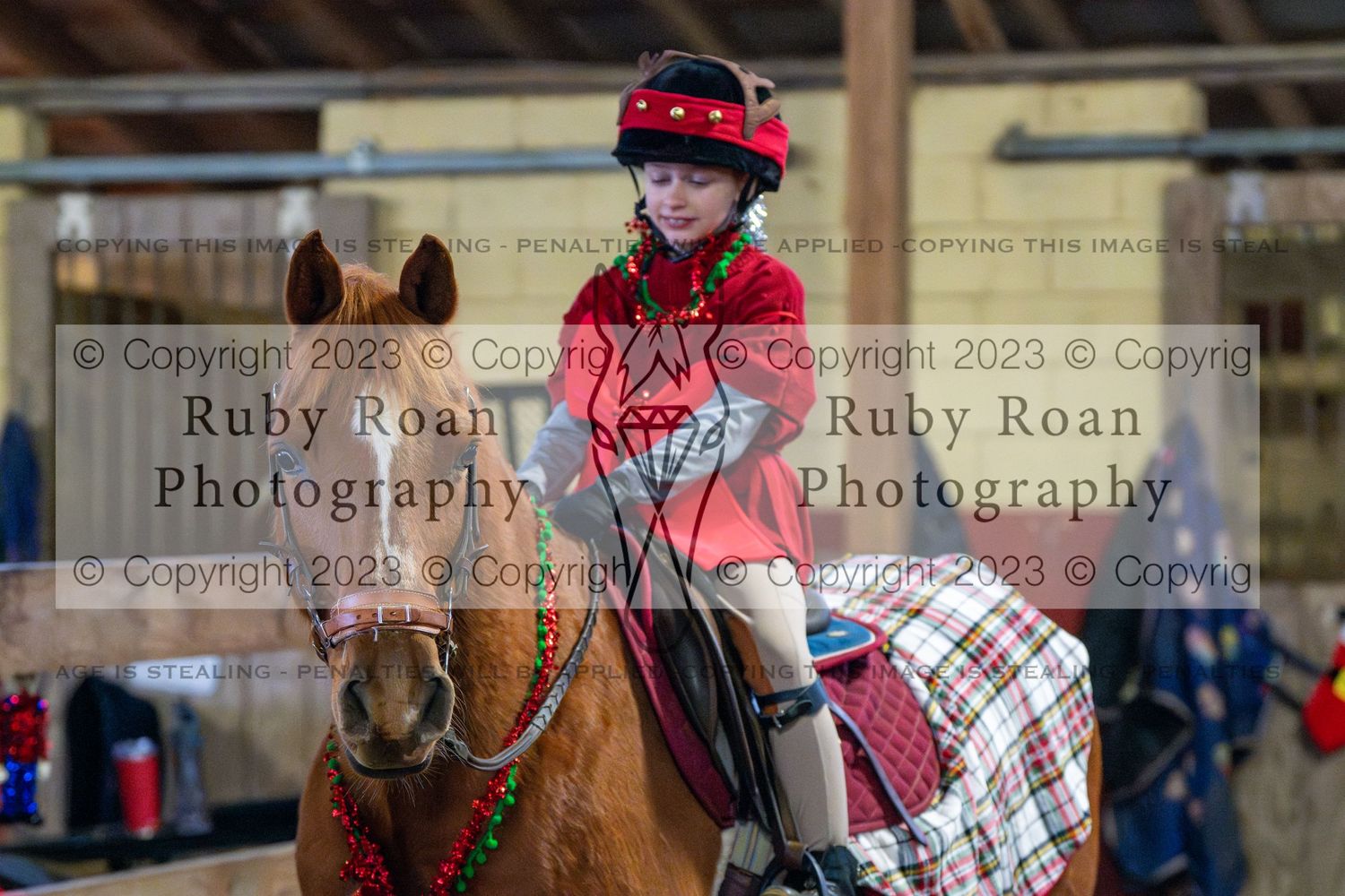 Kid wearing read on a horse in a plaid blanket