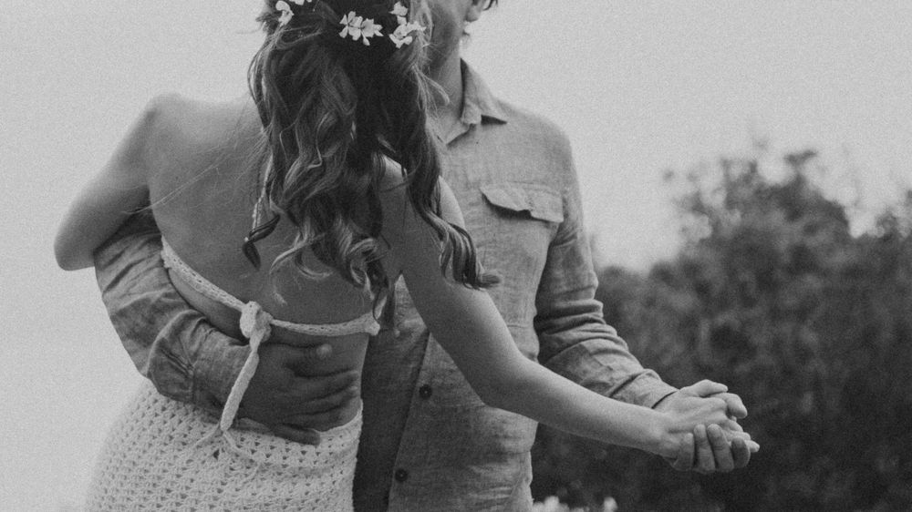 A romantic black and white photo showing a couple dancing outdoors.