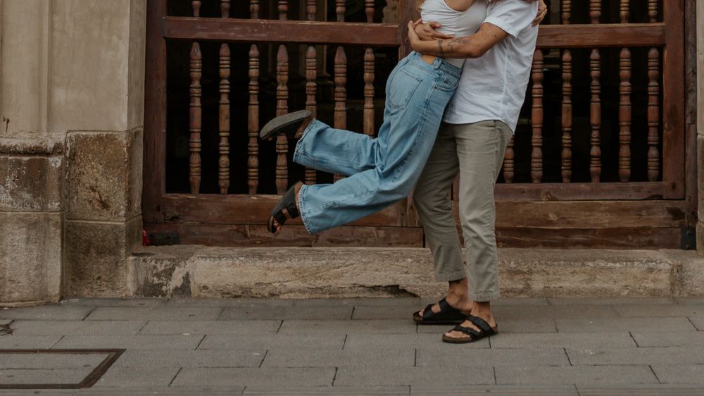 A playful lift captured between two people in front of a wooden door.