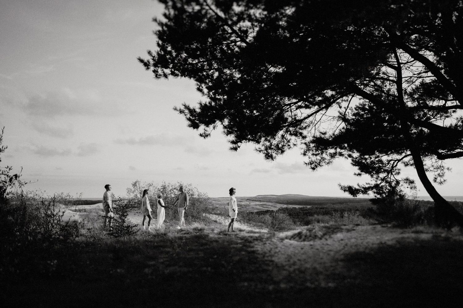 A silhouetted group of people standing on a hilltop against a cloudy sky.
