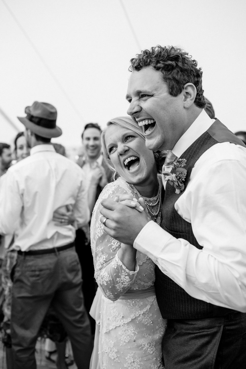 A black and white candid moment of joyful bride and groom on the dance floor during their backyard wedding celebration