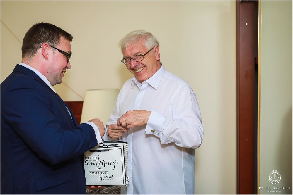 Two men exchange items while standing in a room.