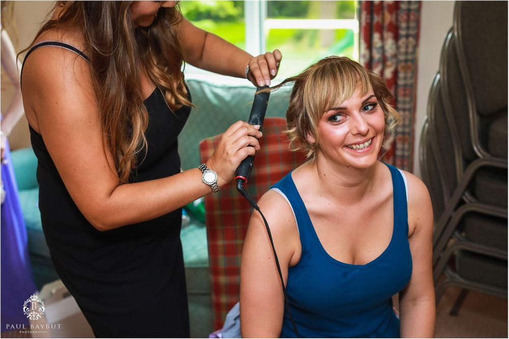A person getting their hair styled while seated in a blue top.