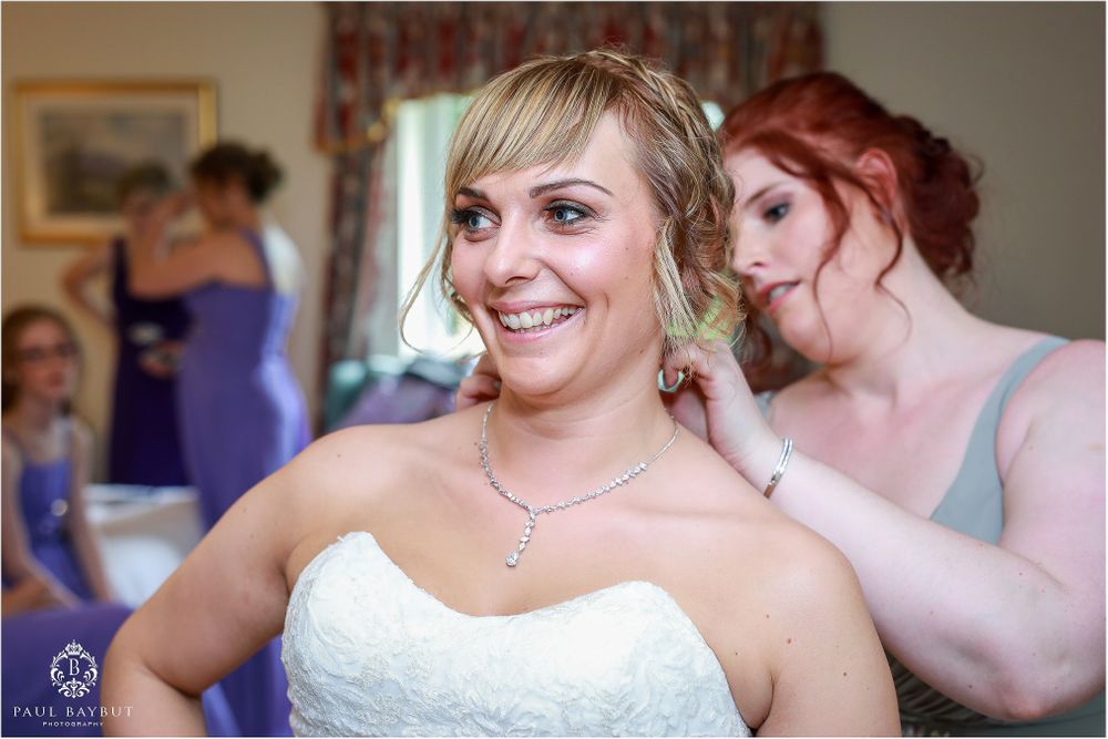A candid wedding preparation moment showing final touches being made to the bride's appearance.