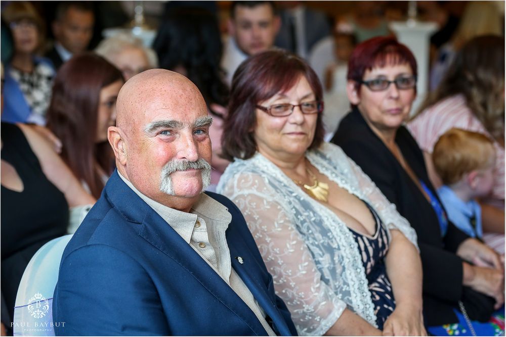 Wedding guests watching the ceremony from decorated chairs in an elegant indoor venue.