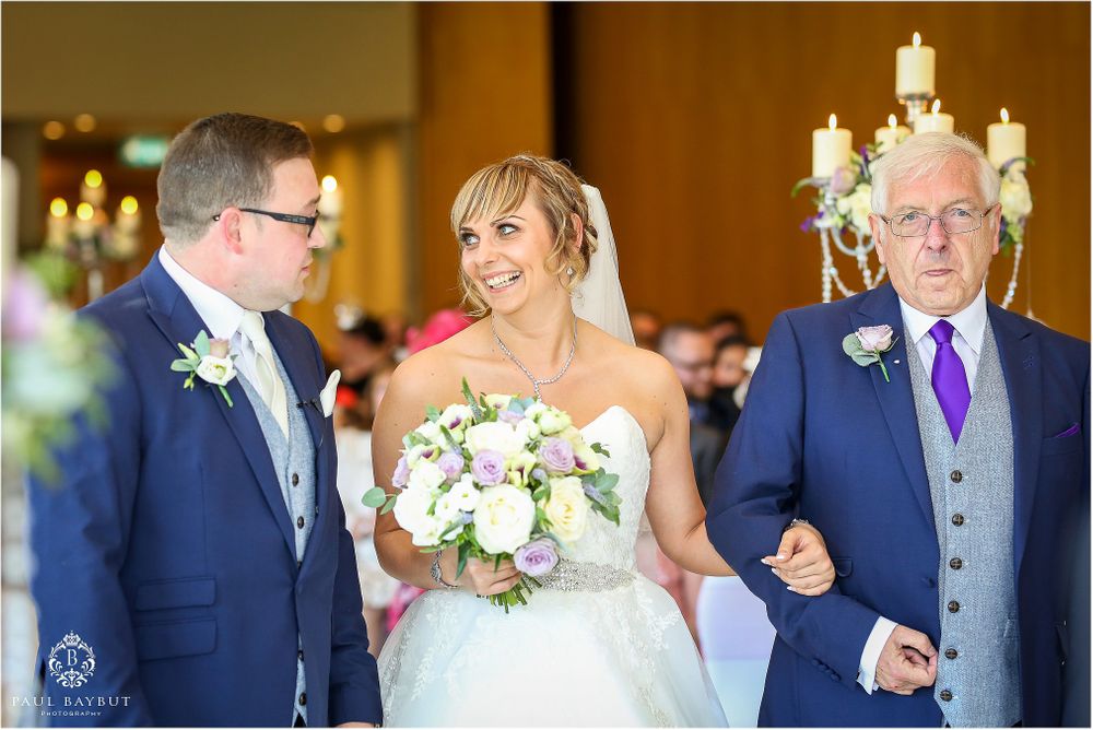 Wedding ceremony with classic decor featuring white candelabras and purple accent details.