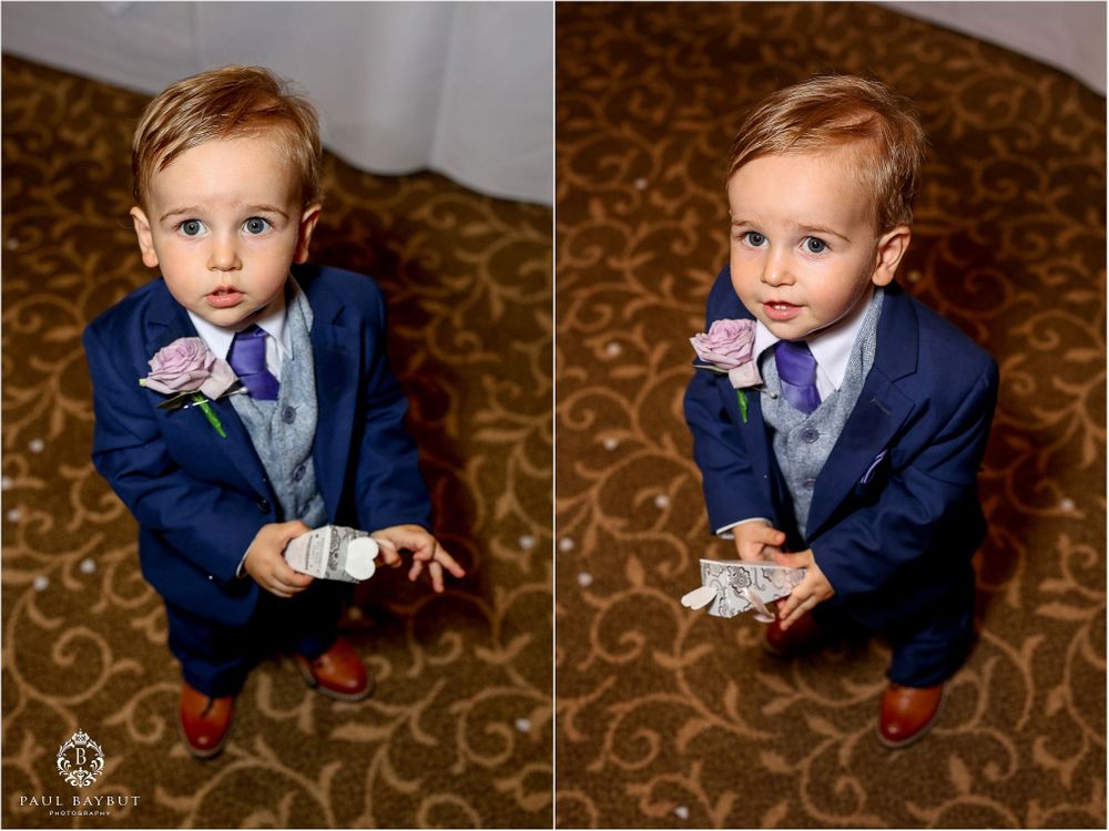 Adorable toddler in navy suit and bow tie making playful expressions at a formal event.