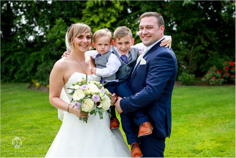 Beautiful outdoor wedding portrait with white rose bouquet on lush green lawn.