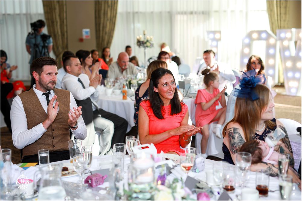 Wedding reception guests enjoying celebration at elegantly decorated tables.