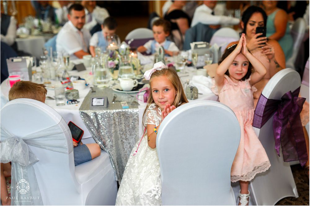 Young guests enjoy a festive reception at an elegant wedding with sparkly silver tablecloths and formal place settings.