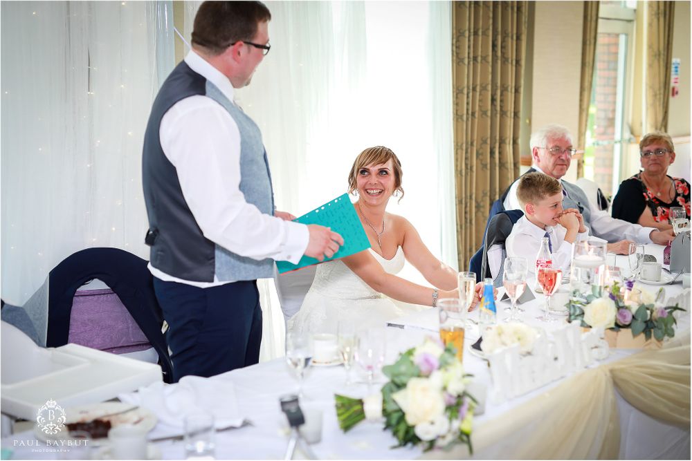 Wedding reception scene showing service staff interacting with guests at an elegantly decorated head table.
