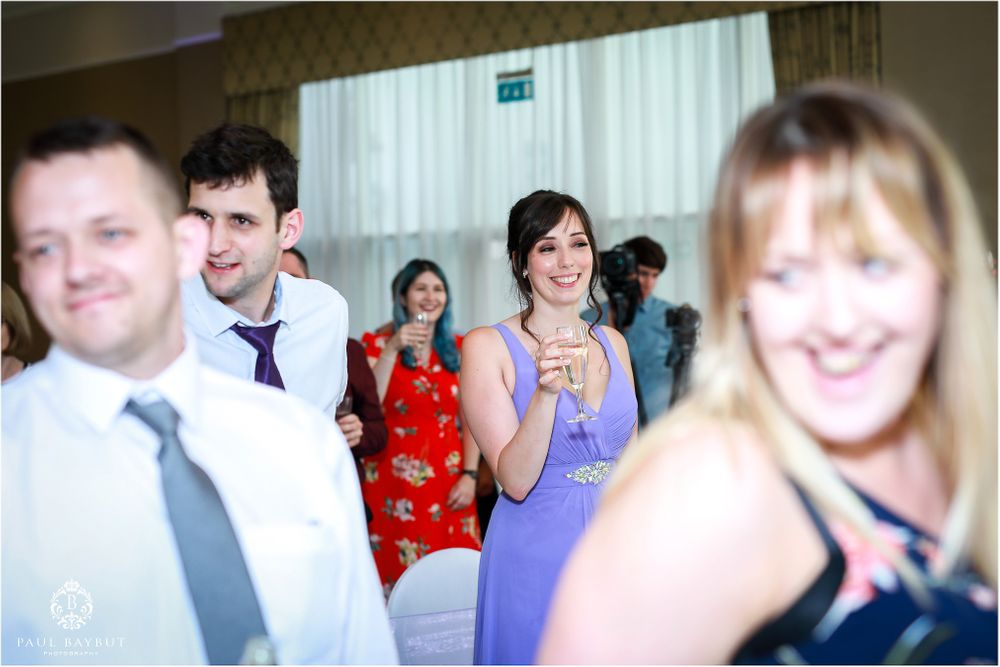 Wedding guests enjoying themselves during reception celebration with drinks and laughter.