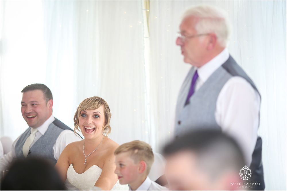 Wedding reception scene with guests enjoying speeches and celebrations indoors.