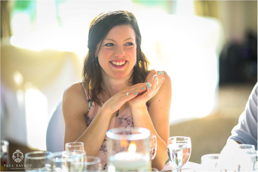 A joyful reaction captured during wedding reception speeches at an elegant indoor venue.