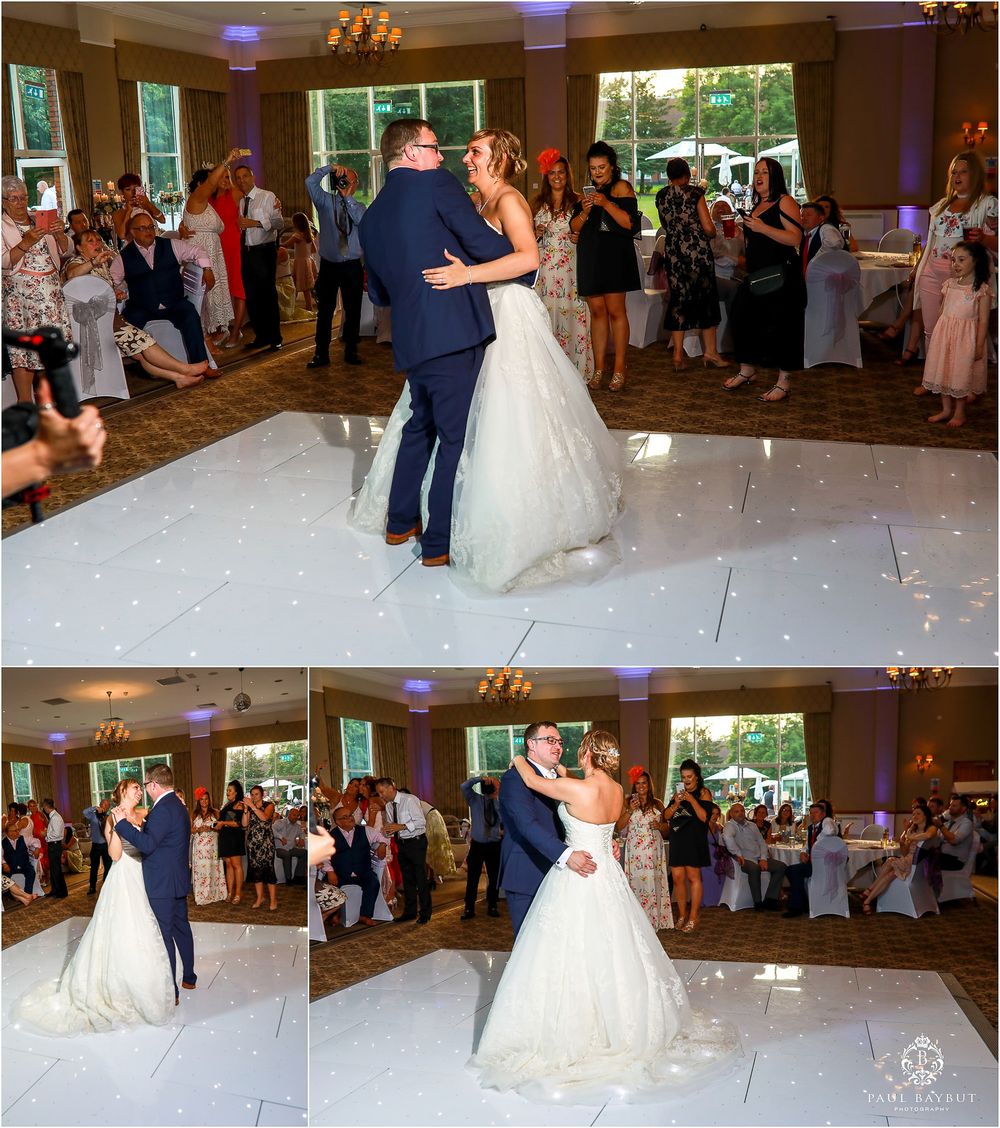 Couple shares their first dance at a wedding reception on a white dance floor surrounded by guests.