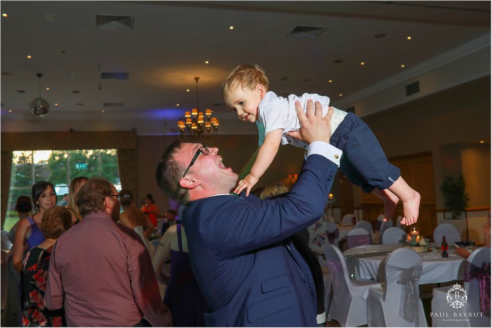 Guest lifts small child in the air during wedding reception celebrations.