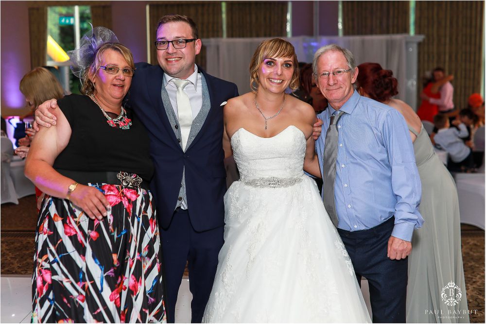 Wedding party poses together for a formal group photo at the reception.