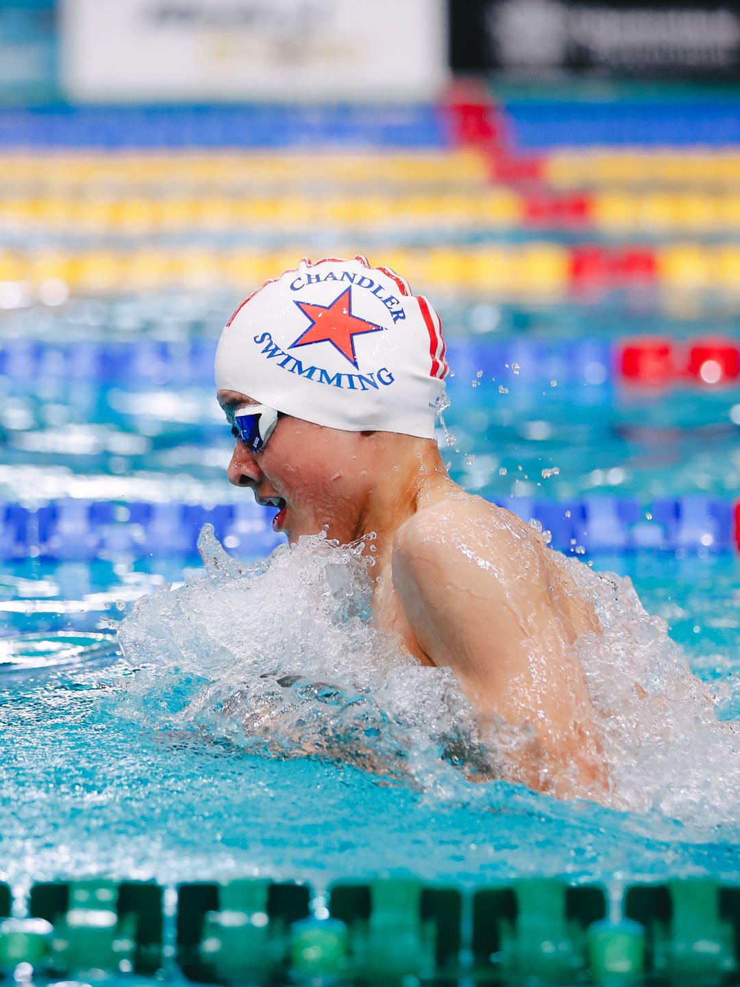 Competitive swimmer performing breaststroke in swimming pool wearing Clovelly swim cap.