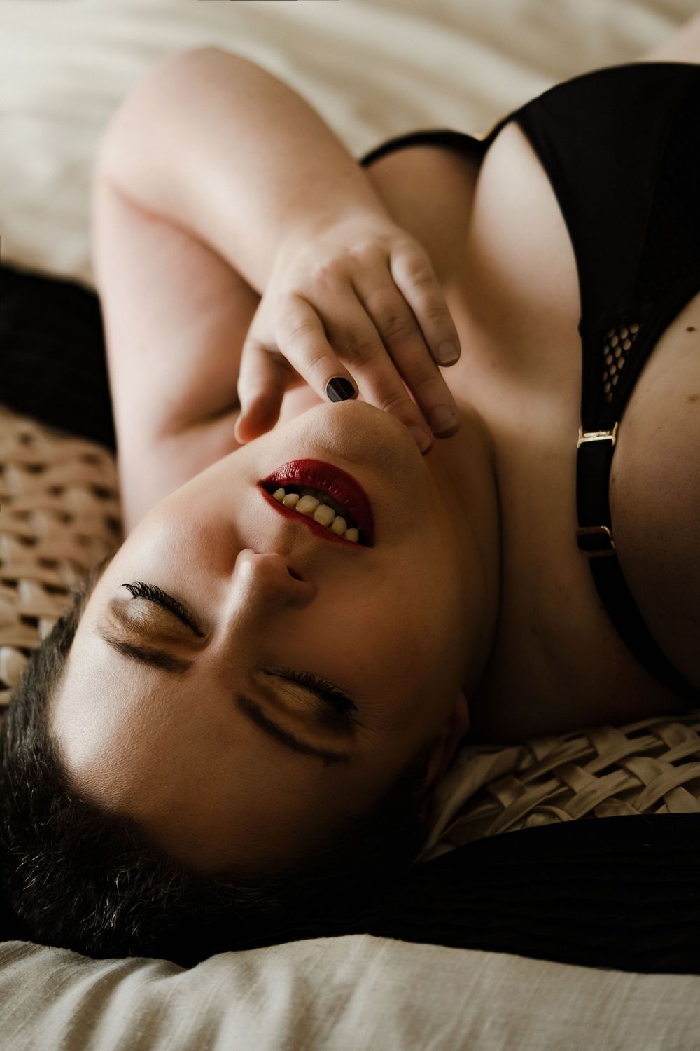 short haired plus size woman in lingerie touching red lips with eyes closed