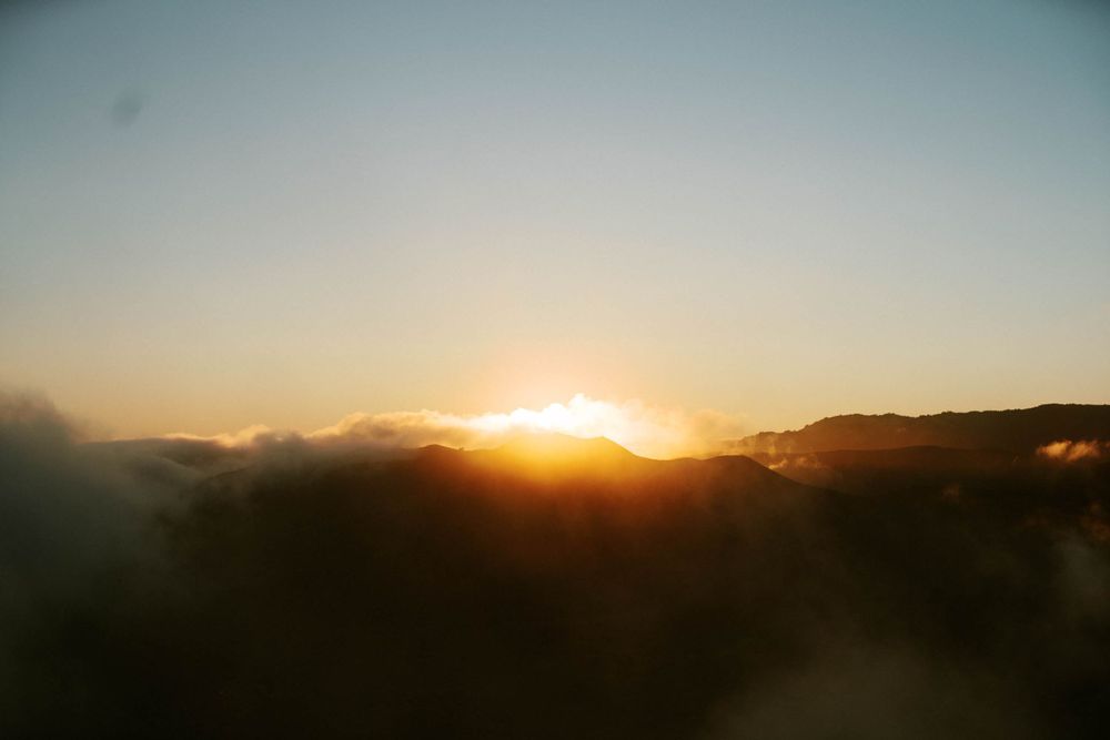 Golden sunburst rising over misty mountain peaks at dawn.