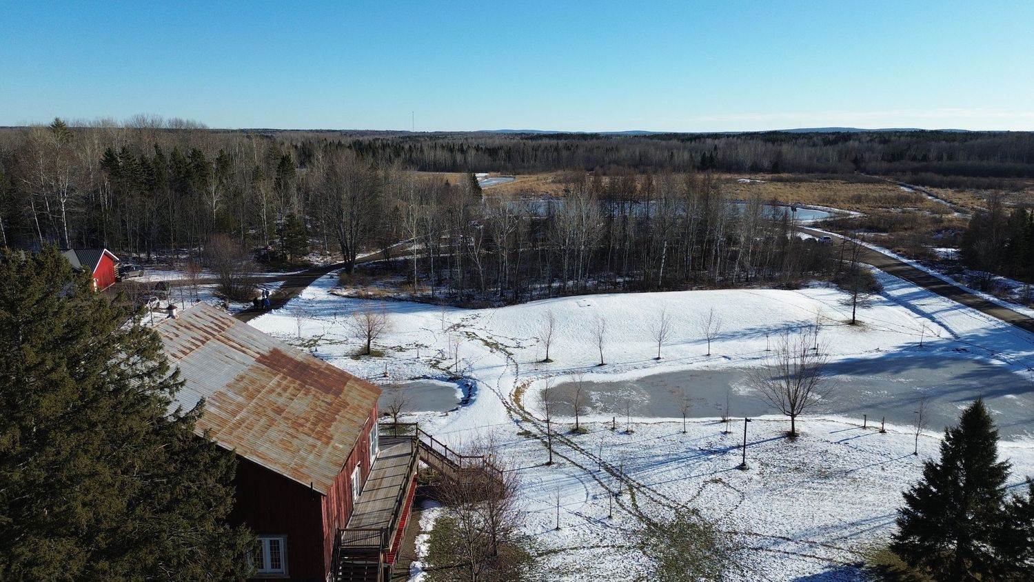 Aerial view of snow-covered grounds with red barn and winter landscape.