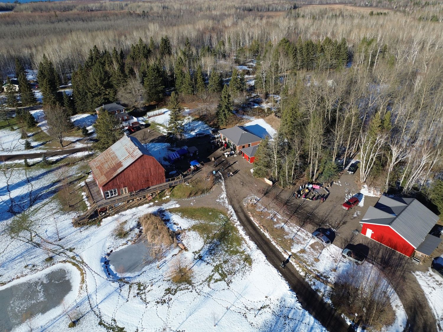 Drone view of red barns and buildings with outdoor winter activity areas and parking.