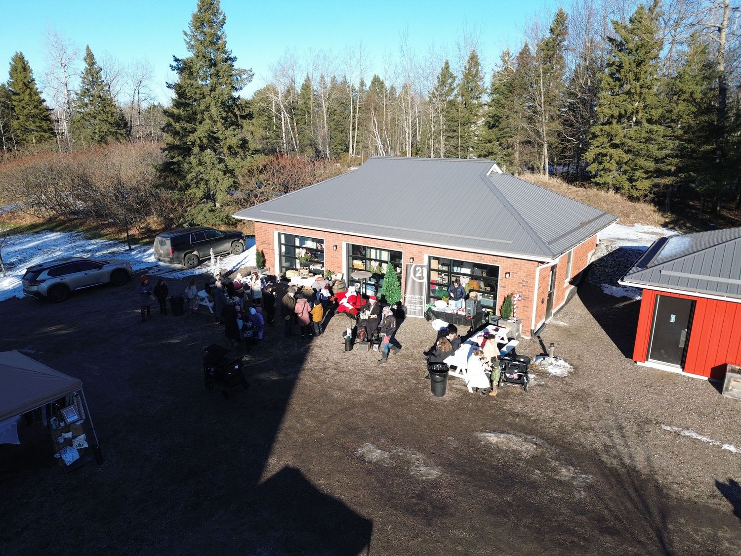 Aerial view of brick building with outdoor seating area and people gathering in winter setting.