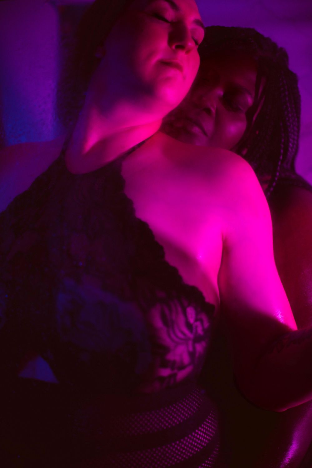 Intimate portrait bathed in vibrant purple and pink lighting.