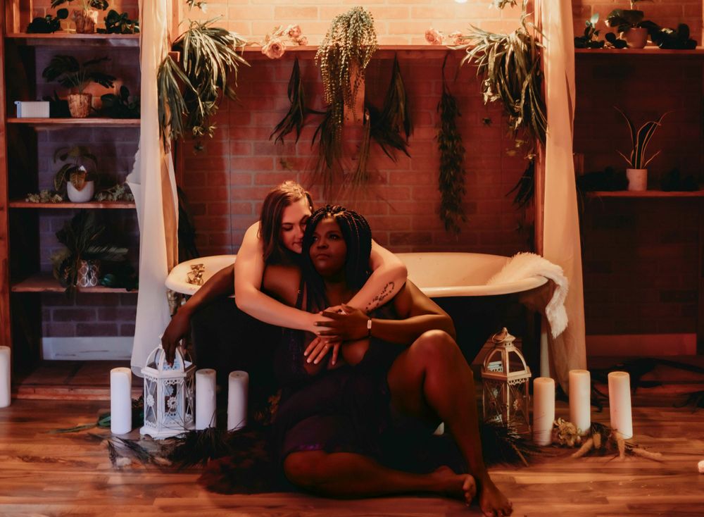 Intimate couples photography in moody setting with candles and white fabric draping.