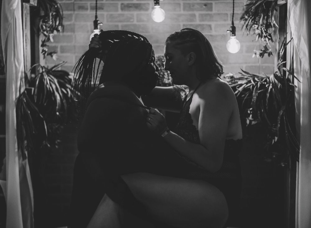 Black and white intimate portrait with hanging lights and fabric backdrop.