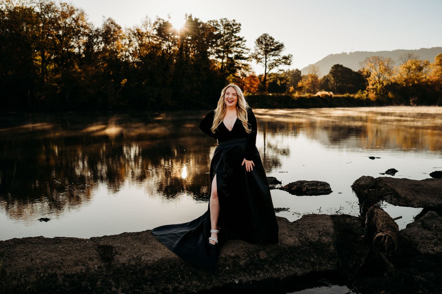 Woman standing on rocks in river wearing a black dress