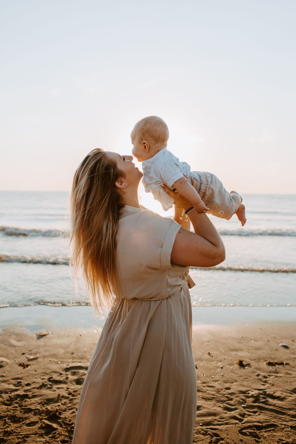 Mother and baby at the beach with sunset and backlight