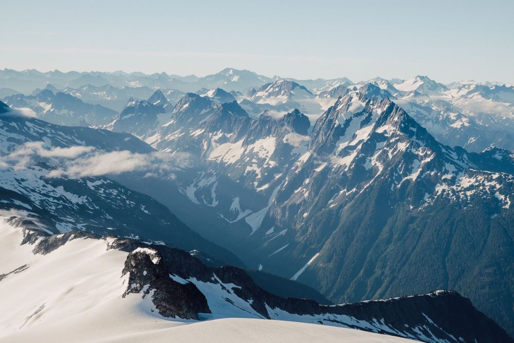 Dramatic mountain landscape with snow-capped peaks and deep valleys stretching into the distance.
