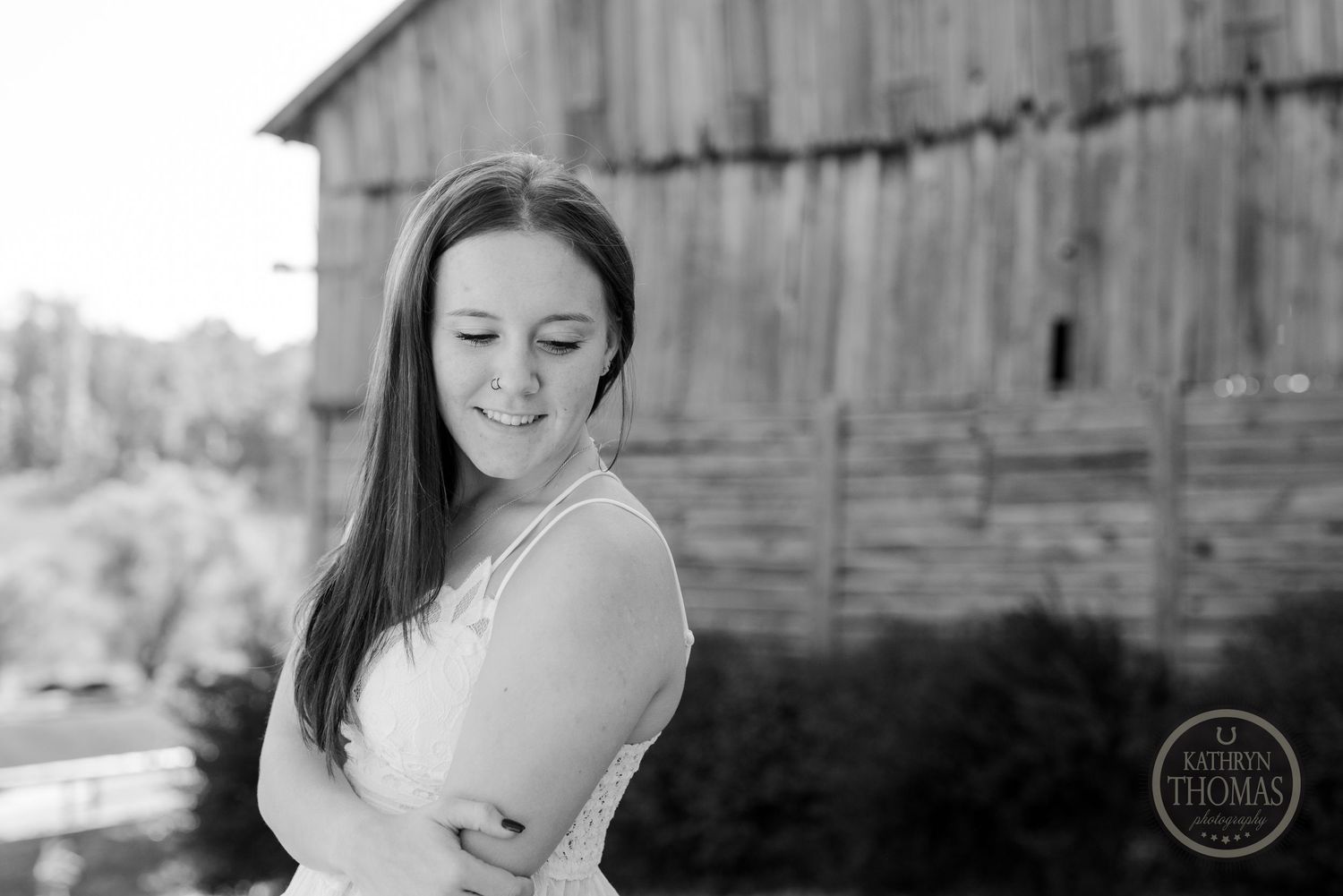 Black and white candid portrait with weathered barn in background.