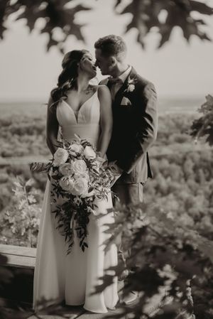 Black and white intimate wedding portrait with a lush bouquet on an outdoor observation deck.