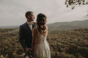 Scenic mountain wedding portrait on wooden observation deck during golden hour.