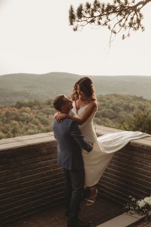 A joyful wedding moment captured on a scenic overlook deck as the couple shares an intimate dance.