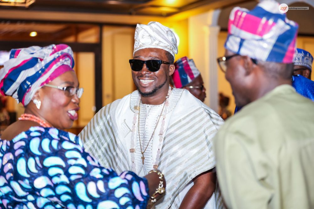 Guests in colorful Nigerian traditional Yoruba attire socializing at a wedding celebration.