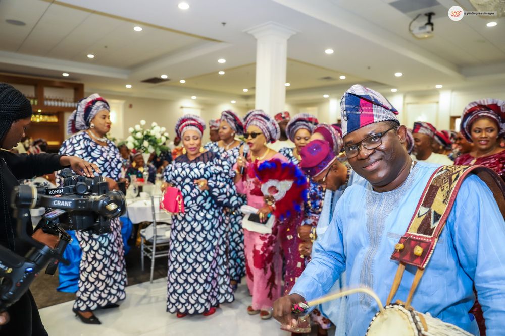 Guests in matching blue ankara fabric dance and celebrate at a vibrant Nigerian traditional wedding reception.