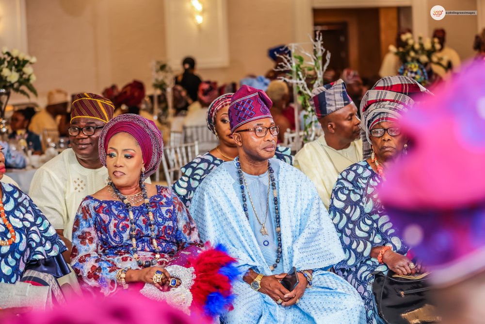 Wedding guests seated in vibrant Nigerian traditional Aso-oke attire at a reception ceremony.
