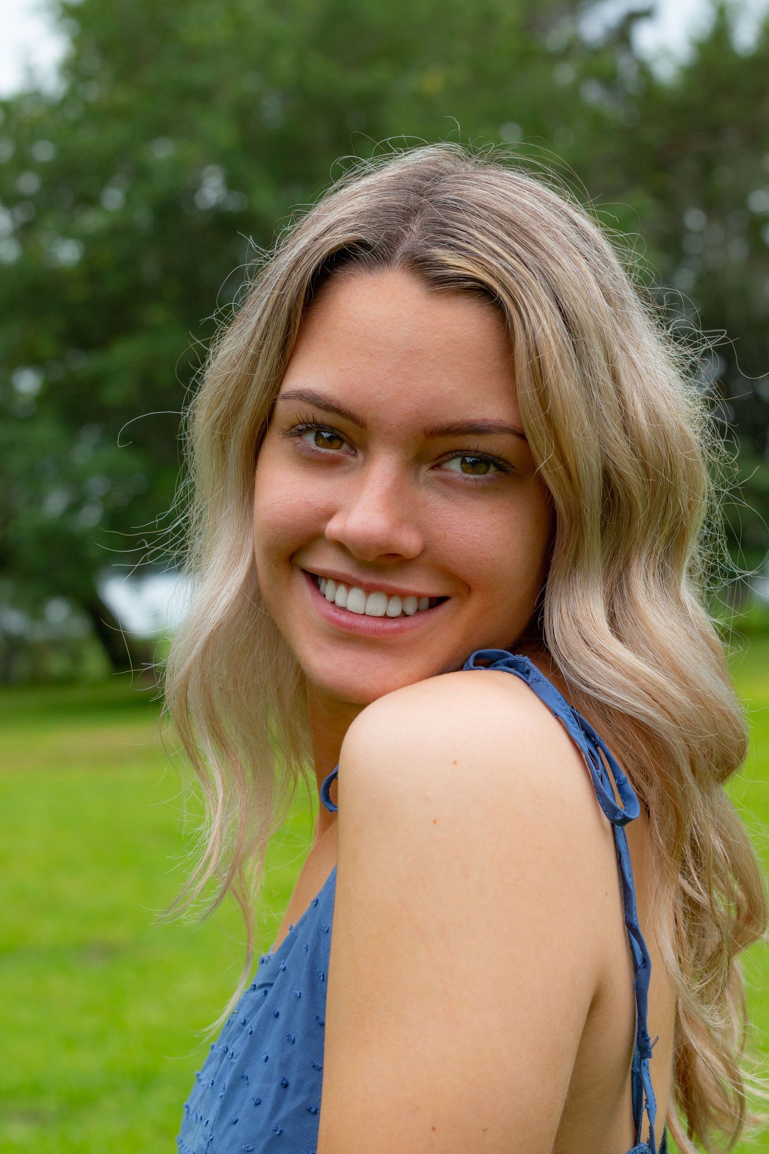 Outdoor photoshoot featuring casual poses in a blue top against a green grass background.