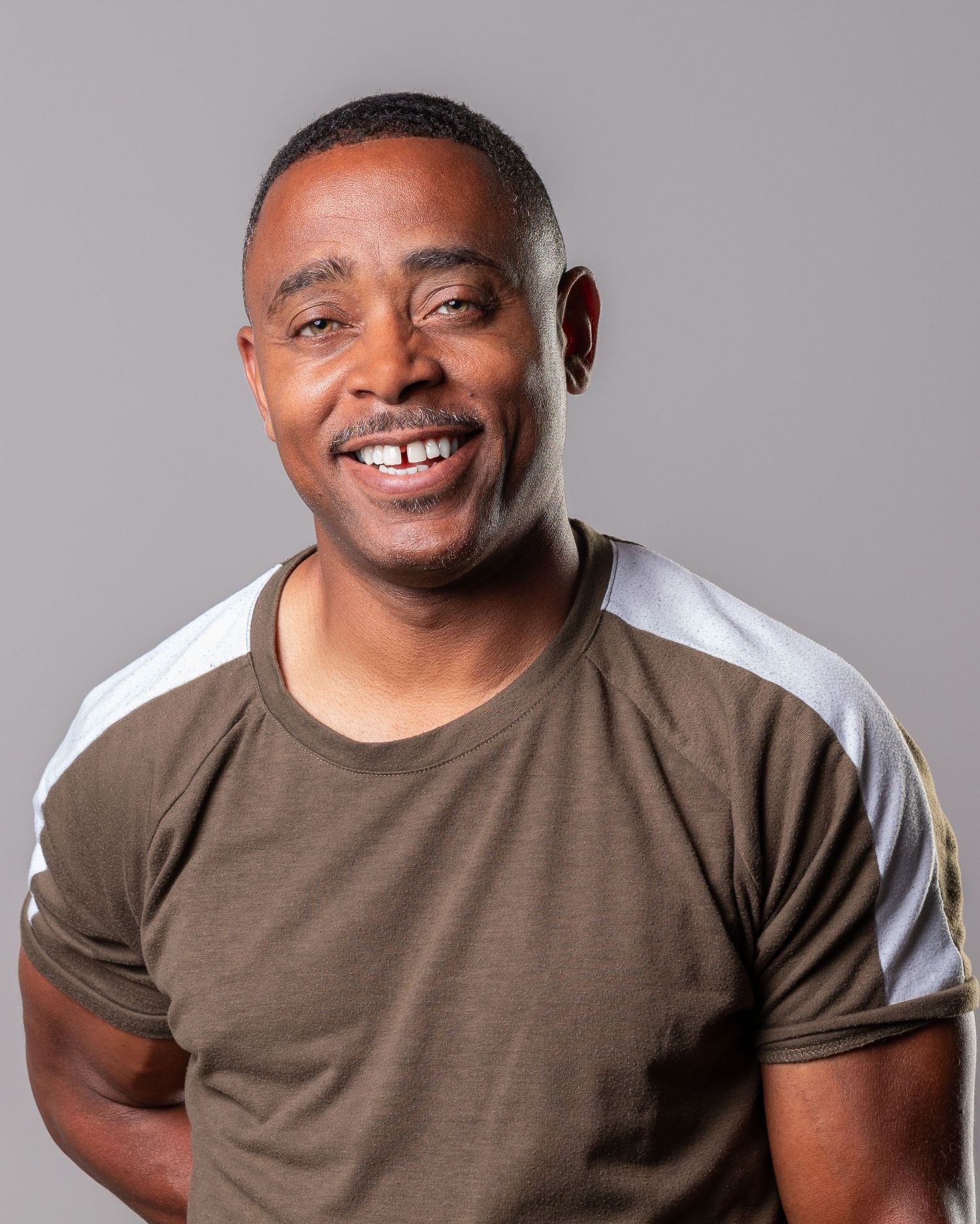 Series of expressive portraits in brown t-shirt against grey background showing various emotions.