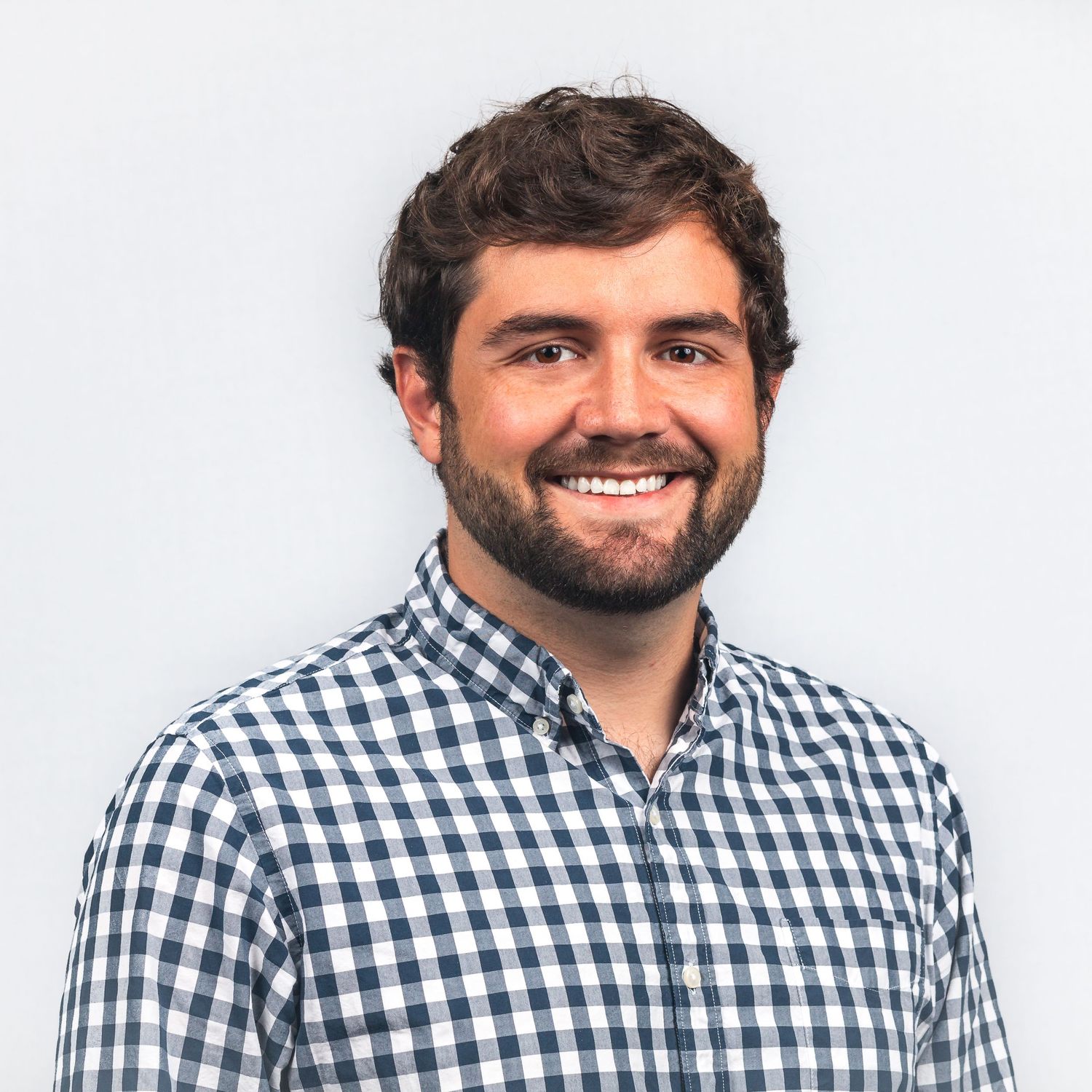 Professional headshot in blue and white checkered button-down shirt.