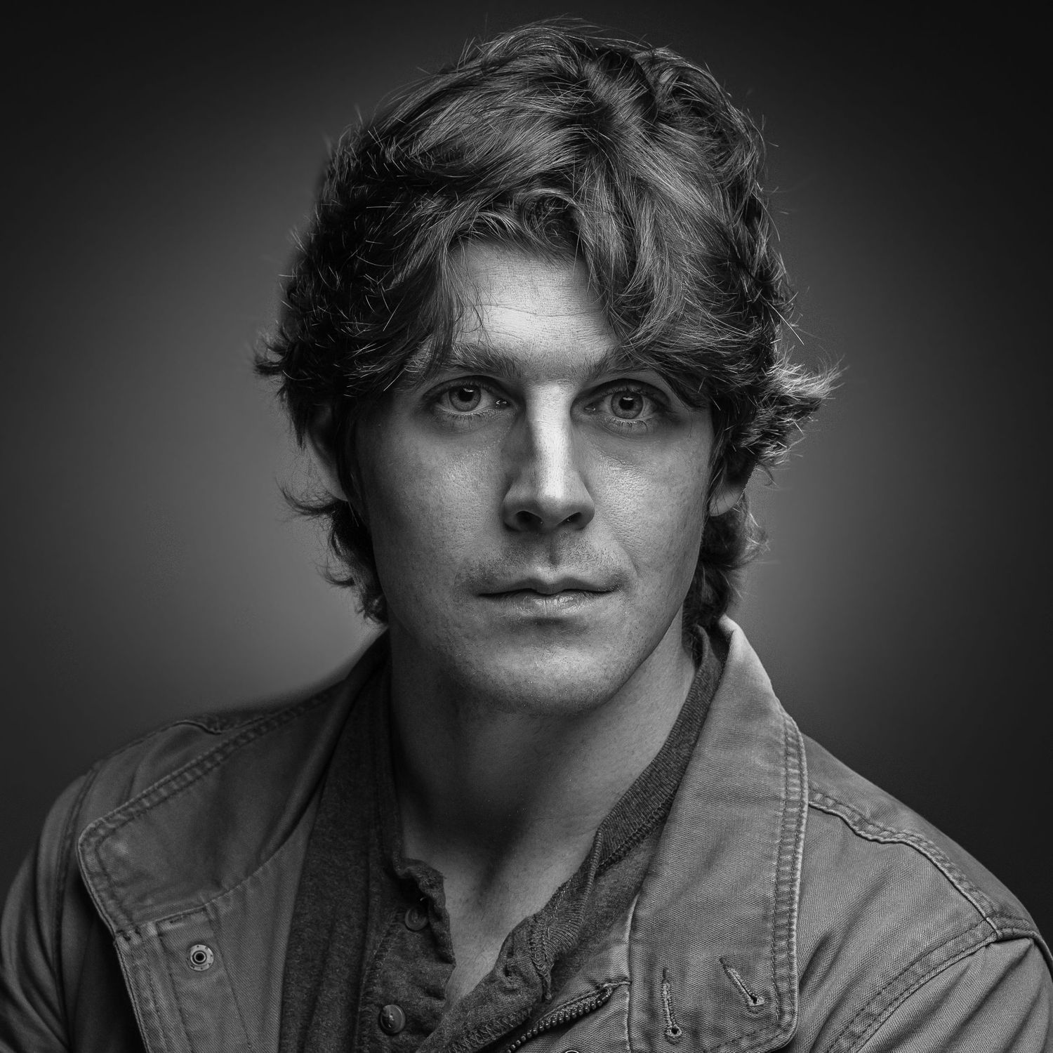 Dramatic black and white headshot series showing different angles against dark background.